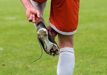 le footballeur ajuste sa chaussure