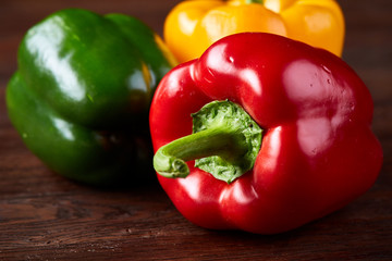 Combination of fresh organic green, yellow and red pepper on rustic wooden background.