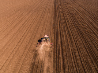 Aerial shot of a tractor cultivating field at spring