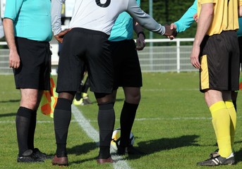 Obraz premium l'arbitre et les capitaines de football au serrage de mains