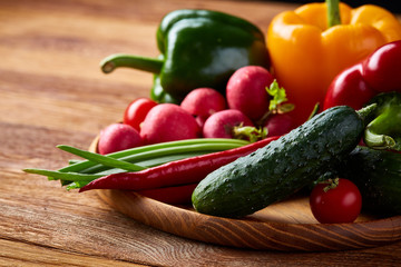 Composition of vegetables on flat plate on wooden table, close-up, selective focus