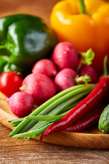 Composition of vegetables on flat plate on wooden table, close-up, selective focus