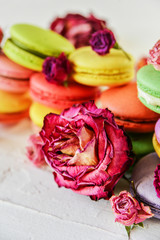 Delicate Fresh Colorful French Macaroons In Pastel Colors With Flowers Roses On A Light Textile Background