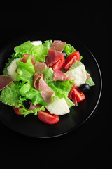 Fresh tasty salad on a glossy black background