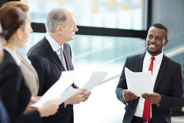 Fototapeta premium Young successful African-american financier making report for colleagues about changes on stock market