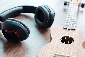 Obraz na płótnie Canvas Headphones and acoustic guitar ukulele brown on wooden floor.