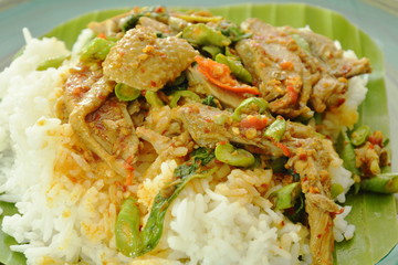 spicy fried duck meat curry with basil leaf and rice on fresh banana leaf