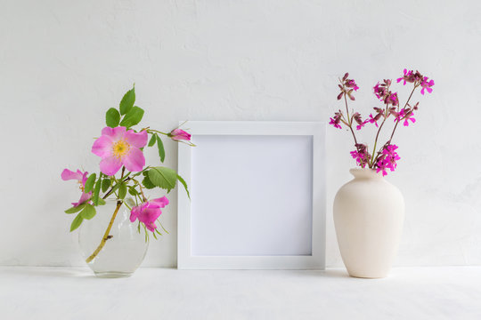 Mockup with a white frame and pink rose hips flowers