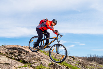 Plakat Cyclist in Red Jacket Riding Mountain Bike Down Rocky Hill. Extreme Sport and Adventure Concept.
