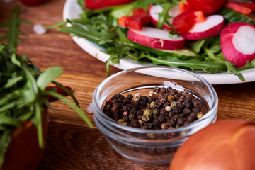Fresh red radish in wooden bowl among plates with vegetables, herbs and spicies, top view, selective focus.