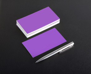 Mockup of business cards and pen at black leather background.