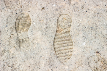 Footprints in the sand. Traces of shoes on sandy shore