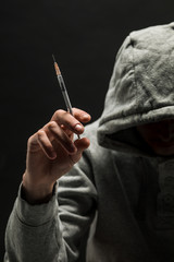 Addict in gray hoodie on the head suffers from addiction on a dark black background