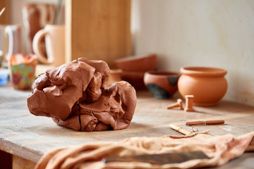 Adult male potter master modeling the clay plate on potter's wheel. Top view, closeup, hands only.