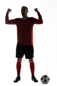 Silhouette Of Young Football Player Victory Scream Arms Up With Soccer Ball Isolated On White Background