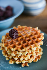 Round waffles with fresh blackberries and icing sugar on wooden background rustic