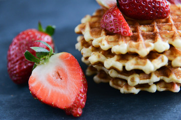 Round waffles with fresh strawberries, on dark background
