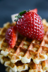 Round waffles with fresh strawberries, on dark background