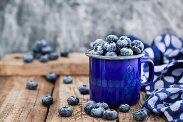 Fresh ripe blueberries and in blue enamel mug