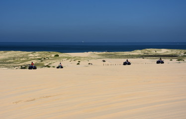 Happy quad bikers driving in sand dunes at Anna bay (Newcastle, NSW, Australia). Active people in outdoor activity driving quad on coastal desert beach.