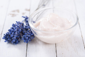 cosmetic cream and lavender flowers on white wood table background