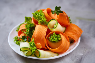 Artistically served vegetable salad with carrot, cucumber, letucce over white background, selective focus