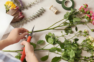 Female florist pruning stem at table, top view