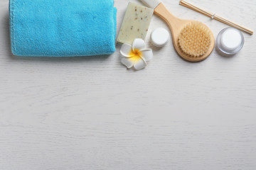 Flat lay composition with spa cosmetics and towel on wooden background