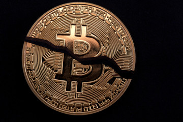 Cracked on two pieces bitcoin isolated on black background
