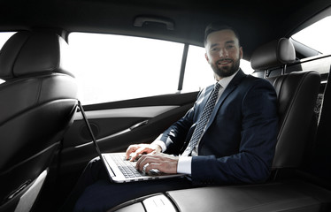 young businesswoman working on her laptop while sitting in the car