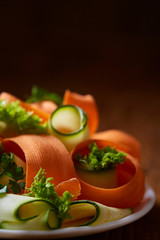 Artistically served vegetable salad with carrot, cucumber, letucce over wooden background, selective focus