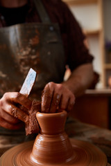 Portrait of a male potter in apron molds bowl from clay, selective focus, close-up