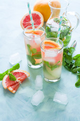 Refreshment grapefruit cocktail with mint on mint color background. Healthy citrus summer drink.