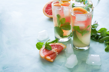 Refreshment grapefruit cocktail with mint on mint color background. Healthy citrus summer drink.