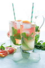 Refreshment grapefruit cocktail with mint on mint color background. Healthy citrus summer drink.