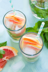 Refreshment grapefruit cocktail with mint on mint color background. Healthy citrus summer drink.