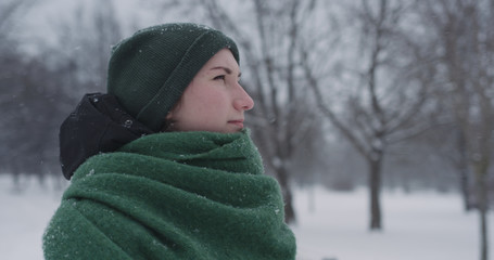 Fototapeta na wymiar girl standing in park on winter day under snowfall