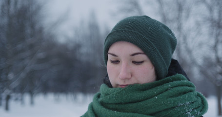 girl standing in park on winter day under snowfall