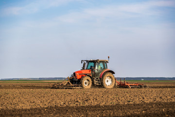 Fototapeta na wymiar Tractor cultivating field at spring