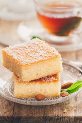 Two slices of homemade semolina cake on a wood vintage rustic table background with mint tea