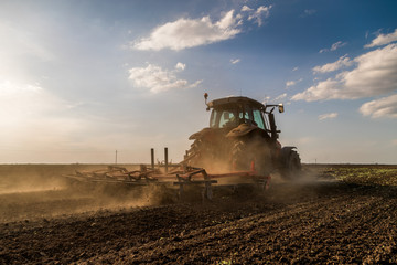 Tractor cultivating field at spring