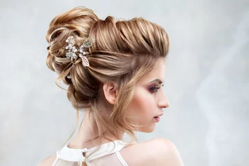  Jonge mooie bruid met een elegant hoog kapsel. Bruiloftskapsel met het accessoire in het haar © Ulia Koltyrina