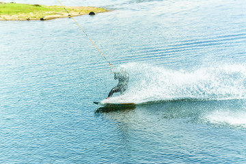 wakeboarder jumps from a springboard behind a rope and makes a wave on the water