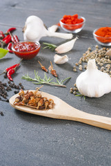 fresh and dried chili fruits, peppercorn, pepper powder, sauce and garlic, bay leaves on old black wooden table background