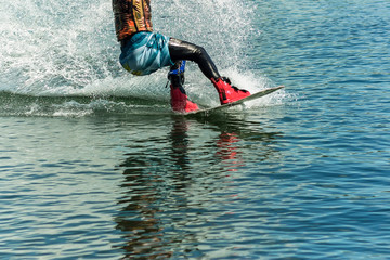 wakeboarder jumps from a springboard behind a rope and makes a wave on the water