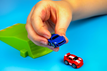 Child playing with cars on blue background.