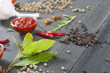 fresh and dried chili fruits, peppercorn, pepper powder, sauce and garlic, bay leaves on old black wooden table background