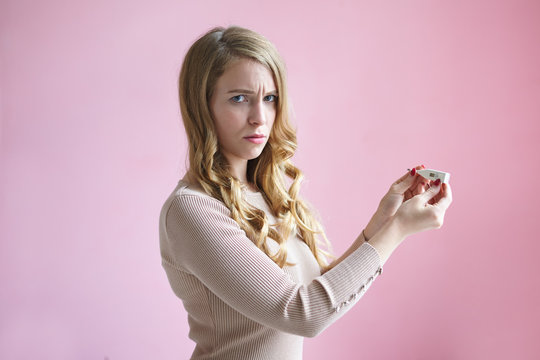 Isolated horizontal picture of frustrated upset young European lady with blonde wavy hairstyle frowning, feeling worried and scared, having positive pregnancy test, not sure about her decision.