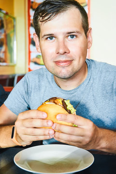 Man is holding an appetizing burger in hands