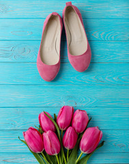 Women's shoes and bouquet of pink tulips on a wooden background.